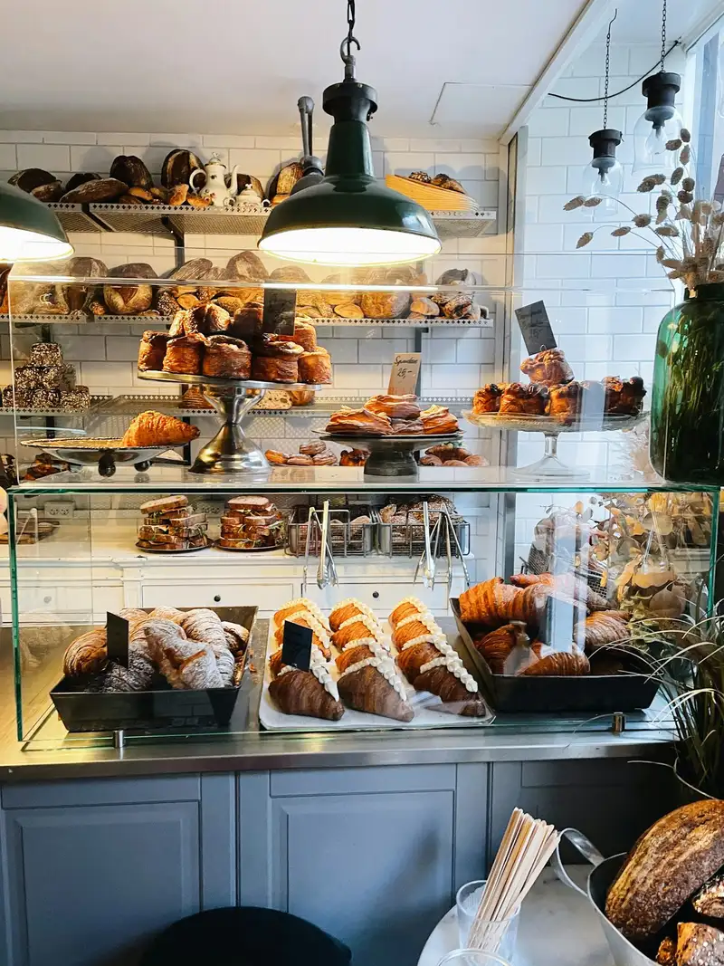 Banner de site com a foto de uma vitrine de padaria com croissants e pães, o título "Do forno para o seu café." e o botão "Encomendar bolo".